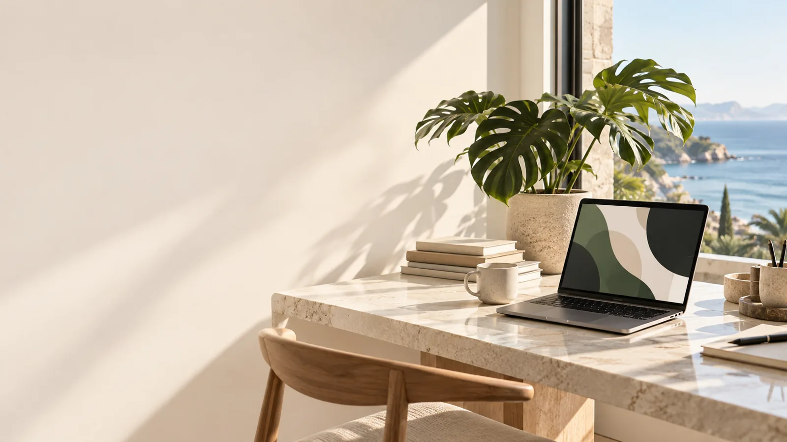 Laptop y planta junto a una ventana en un espacio de trabajo luminoso